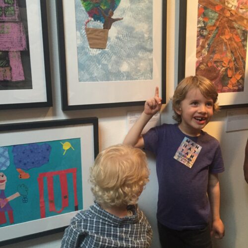 A group of children looking at framed artwork in an art gallery.
